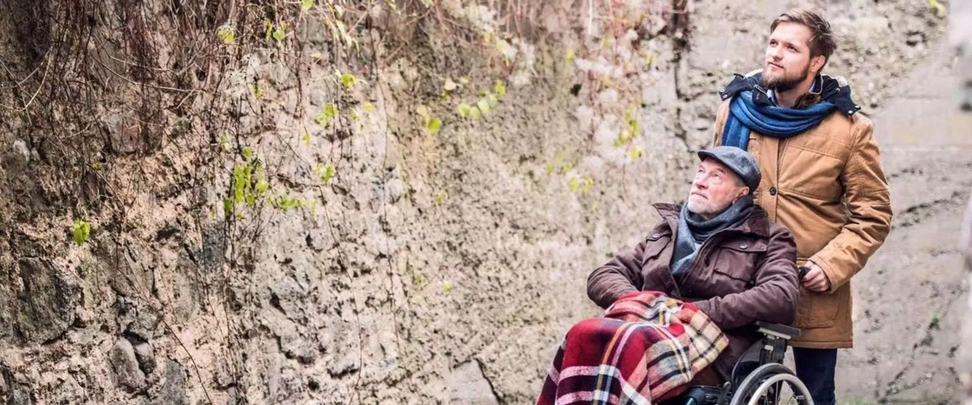 Nachbarschaftshelfer schiebt Rentner im Rollstuhl