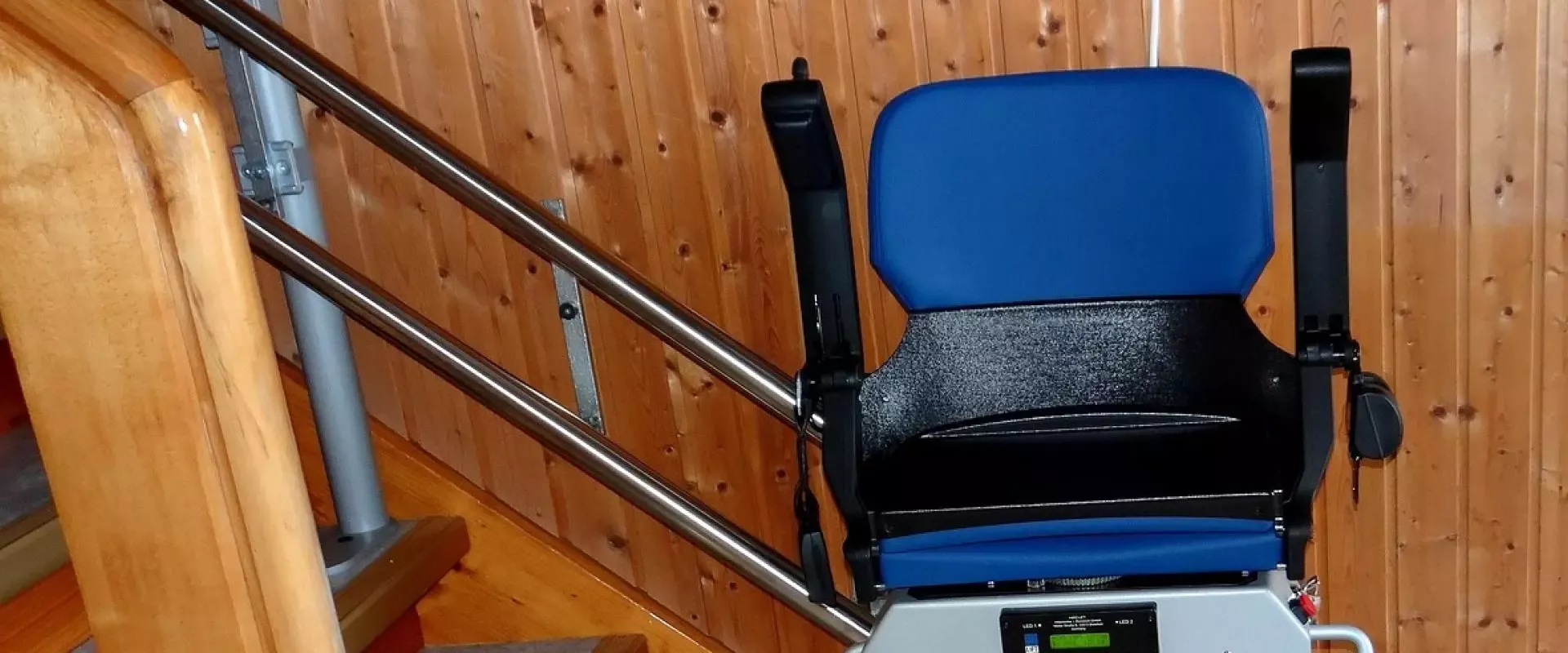 Eingebauter blauer Treppenlift am Treppenanfang einer Wohnung, ohne Person