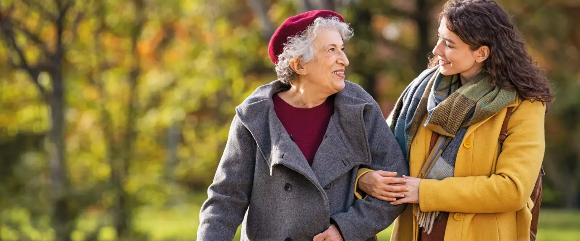 Foto: Seniorin und Schwiegertochter spazieren Arm in Arm im Park
