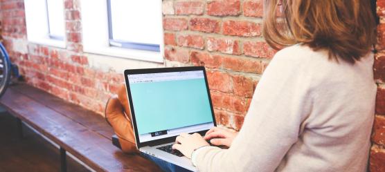 Frau sitzt an Laptop