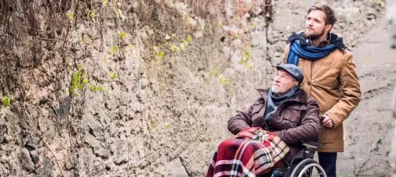 Bild Mann schiebt Rentner im Rollstuhl