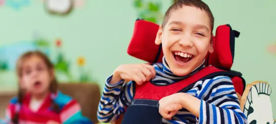 Bild: Kind mit Einschränkungen lacht in die Kamera