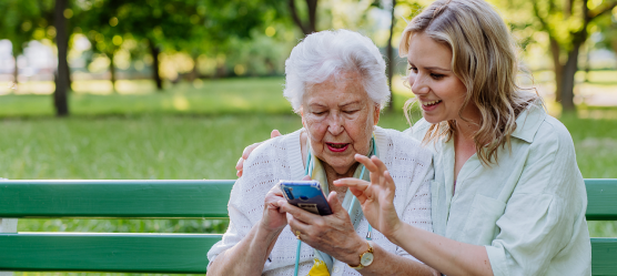 junge Frau hilft älterer Dame mit dem Handy