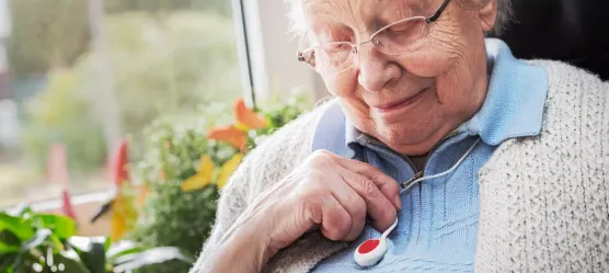 Frau trägt einen Hausnotrufknopf um den Hals